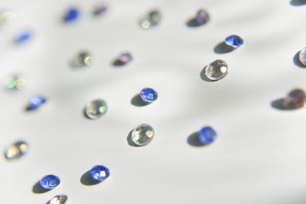 rhinestones of different colors on the white background. Handcraft concept. Selective focus.