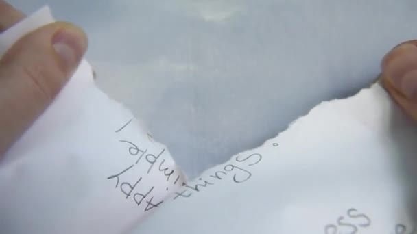 deux mains déchirent la feuille de papier sur le fond bleu et blanc 