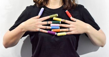 Dikiş iplikleri, siyah arkaplandaki kadın parmaklarının uzaması olarak gösteriliyor. seçici odak