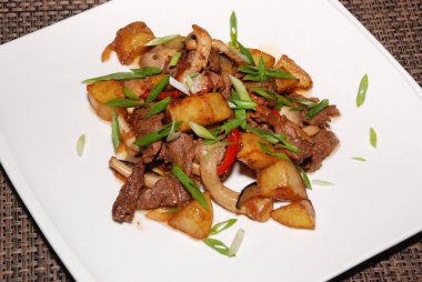 Yeşil soğanlı kızarmış biftek, beyaz tabakta mantar ve patates. seçici odak