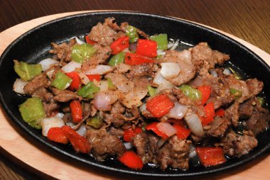 Dökme demir tavada yeşil ve kırmızı dolma biberli kızarmış biftek ve soğan. seçici odak