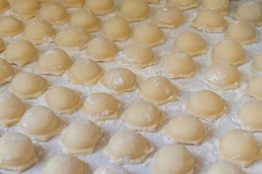 Çiğ altın hamur tatlısı, un buharı ile birlikte masanın üzerinde yatıyor. Hamur köfteleri. Yarı bitmiş ürünler masaya eşit olarak serilmiş.