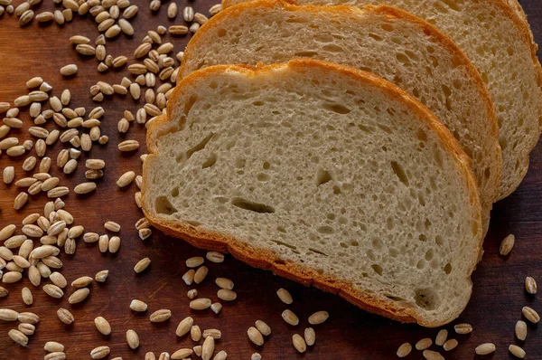 Φέτες Λευκού Ψωμιού Σκουρόχρωμη Επιφάνεια Και Χυμένοι Κόκκοι Σιταριού — Φωτογραφία Αρχείου