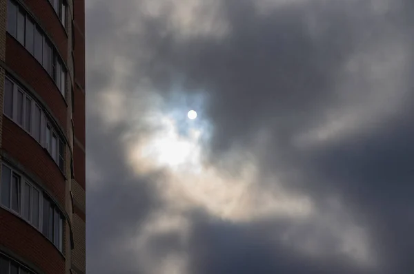 The sun breaking through the clouds in an urban area. A sharp change in weather. Clouds hanging over the house