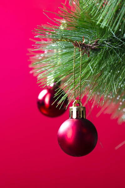 Christmas pine branch with red balls close-up on a red background — Stock Photo, Image