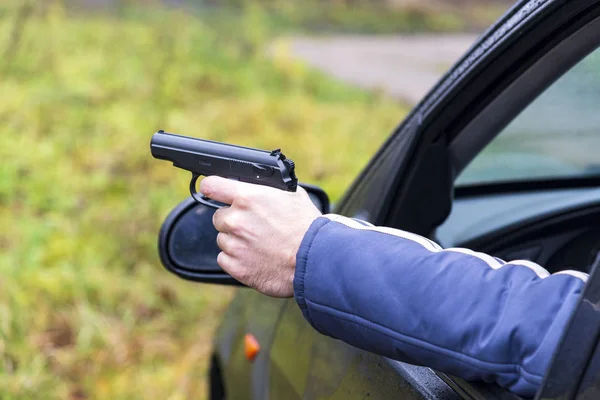 Mann mit Waffe am Steuer eines Autos, männliche Hand mit Waffe — Stockfoto