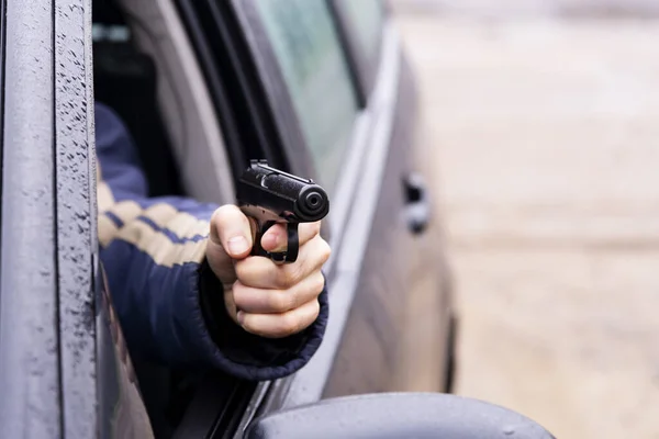 Hombre con un arma conduciendo un coche, mano masculina con un arma — Foto de Stock