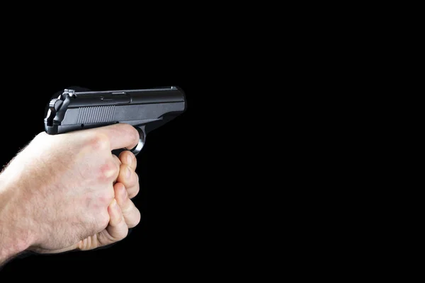 Ein Mann mit einer Waffe in der Hand auf schwarzem Hintergrund. Killer mit Waffe — Stockfoto