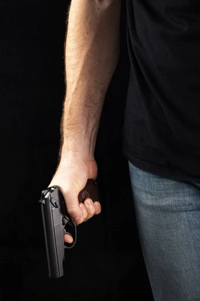 Ein Mann mit einer Waffe in der Hand auf schwarzem Hintergrund. Killer mit Waffe — Stockfoto