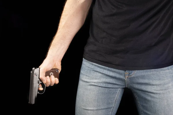 Ein Mann mit einer Waffe in der Hand auf schwarzem Hintergrund. Killer mit Waffe — Stockfoto