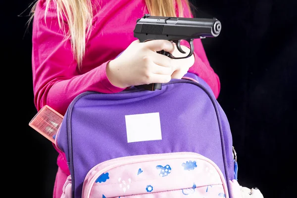 La chica esconde un arma en una mochila escolar. Covert portando armas para protegerse. Armas en la escuela, asalto en la escuela, disparos — Foto de Stock