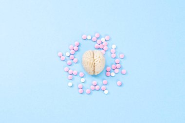 Brain on a blue background with white and pink pills. Some pills for the brain. Symbolical for medicines, psychopharmaceuticals, nootropics and other medicines. Medicine. Brain treatment clipart