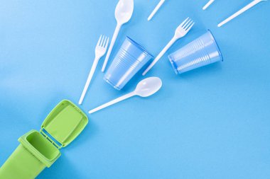 Mavi arka plan ve çöp konteynırında ev atıkları. Plastik, polietilen, karton, kağıt, cam tasnif konsepti. Çevre koruma, ekoloji