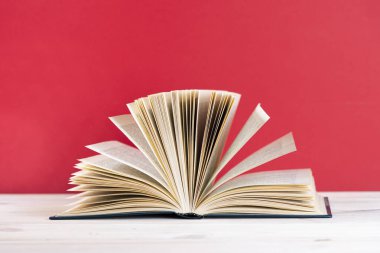 Kaliteli eski defter, günlük ahşap güverte masasında ve kırmızı arka planda sayfaları olan kompozisyon. Kitap istiflemek. Okula dönelim. Uzayı kopyala Eğitim