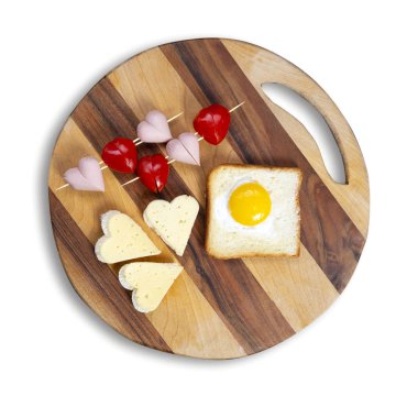 Yemek pişirme, beyaz arka planda izole edilmiş sandviçler kalp şeklinde atıştırmalıklar, üst manzara. Kalp şeklinde sosisler ve ahşap tepside kıtır ekmekli kiraz domatesli sandviçler. Sevgililer Günü