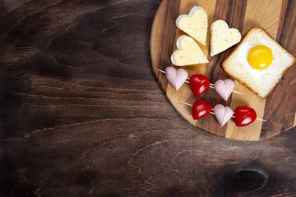 Cooking, sandwiches, heart-shaped snacks, top view. Heart-shaped sausages and sandwiches with cherry tomatoes with croutons on a wooden table. Valentines Day — Stock Photo, Image
