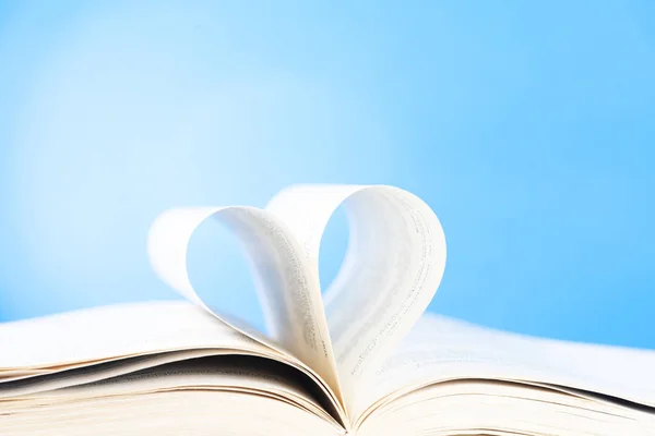 mavi arka plan üzerinde bir kalp şekil kavisli bir kitabın sayfaları