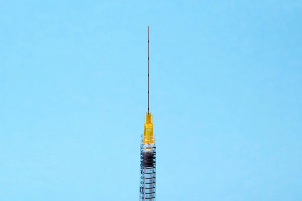 Medische plastic spuit met een naald voor schoonheidsinjecties op een blauwe achtergrond. Therapie concept. Selectieve focus — Stockfoto