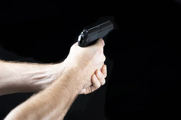 A man with a gun in his hand on a black background. Killer with a gun