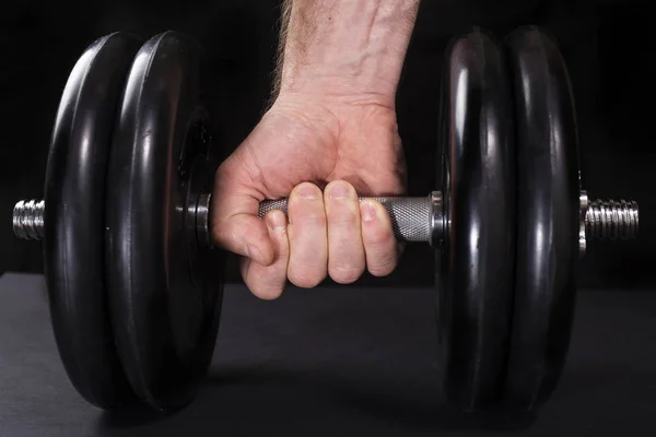 Mężczyzna ręka trzyma stalowe typu ustawienie hantle, sport trening z ciężarem na czarny tło — Zdjęcie stockowe