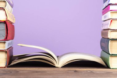 Çok sayıda ciltli kitabın basit bir kompozisyonu, ahşap bir masa üzerinde çok renkli kitaplar ve parlak mavi bir arkaplan. Ben okula geri dönüyorum. Boşluk Eğitimini Kopyala