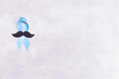 Healthcare and medicine concept - blue prostate cancer awareness ribbon and paper black mustache, achalasia and adrenocortical cancer, on gray background, flat lay, top view, place for text clipart