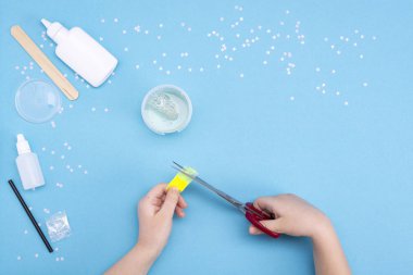 Evde sümük nasıl yapılır? Çocuk sanat projesi. Diy kavramı. Mavi üzerine sümüklü oyuncak yapan çocukların elleri. Adım adım fotoğraf talimatı