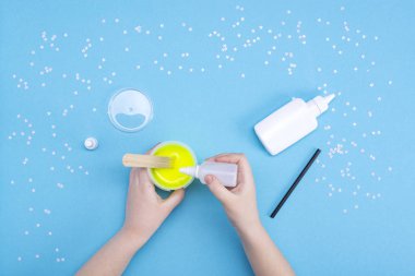 Evde sümük nasıl yapılır? Çocuk sanat projesi. Diy kavramı. Mavi üzerine sümüklü oyuncak yapan çocukların elleri. Adım adım fotoğraf talimatı