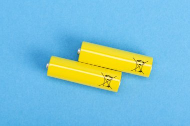 Two yellow batteries on a blue background, top view clipart