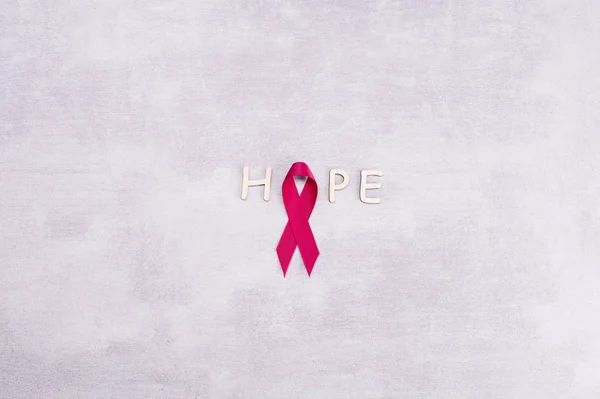 医疗保健和医学概念- -粉色乳腺癌意识带和字母"希望"一词在灰色背景下的文本 — 图库照片