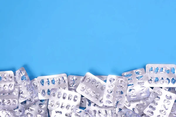 Embalaje vacío de plata para medicamentos, pastillas sobre un fondo azul con lugar para texto — Foto de Stock