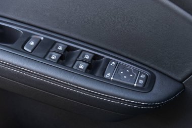 Modern bir arabadaki kapı kontrol panelinin yakın plan görüntüsü. Pencere kontrol paneli, kapı kilidi düğmesi ve ayna kontrollü kol dinlenmesi.