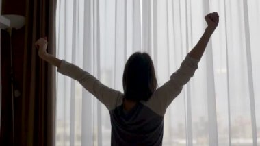 girl wakes up stretches up and opens the window
