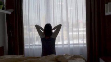 girl wakes up stretches up and opens the window