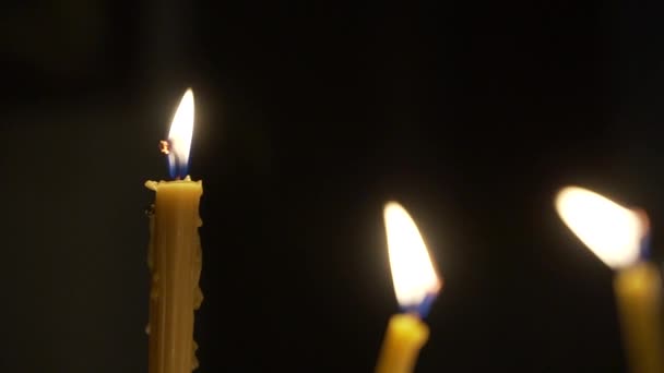 Candles burn in the church camera with movement to the side — Wideo stockowe