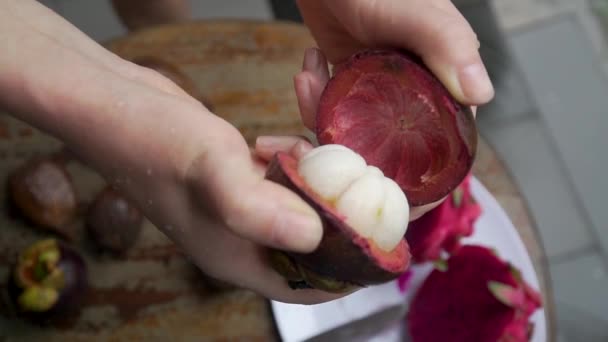 Das Mädchen enthüllt eine Mangostane im Rahmen große Hände im Hintergrund liegen — Stockvideo