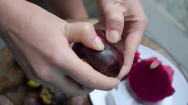 Kız çerçevede bir mangosteen 'i açığa çıkarıyor. Arka planda büyük eller yatıyor. — Stok video