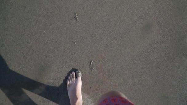 Un hombre camina a lo largo de la playa en el marco solo piernas vista superior arena y olas — Vídeos de Stock