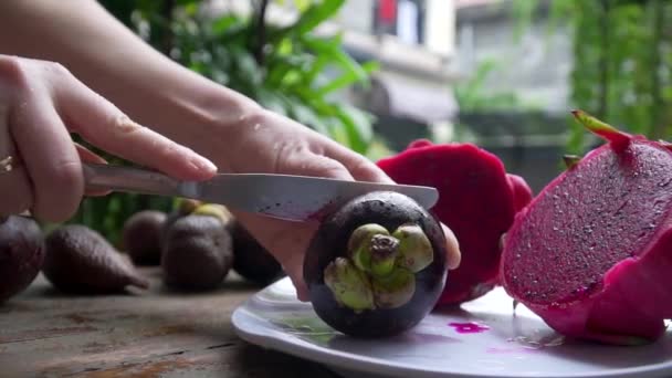 Het meisje snijdt mangosteen in het frame grote handen op de achtergrond ligt draak — Stockvideo