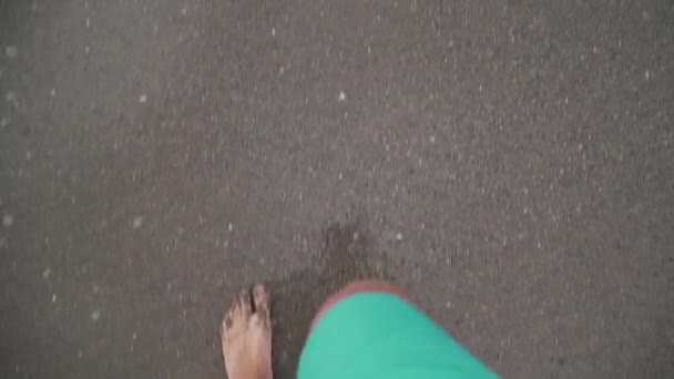 Ein Mann geht entlang des Strandes im Rahmen nur Beine Draufsicht Sand und Wellen — Stockvideo
