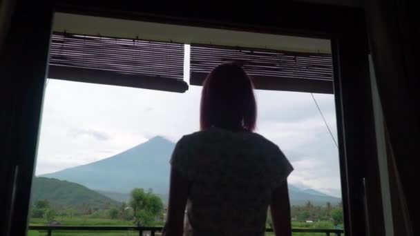 Menina abre cortinas vista do vulcão Agung na ilha de Bali — Vídeo de Stock