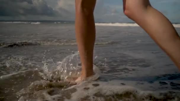 Девушка гуляет по пляжу в раме ног и волн — стоковое видео