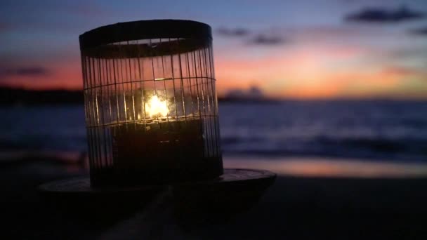 Bali, na oceánu hoří svíčka, obloha zapadajícího slunce už potemněla. — Stock video