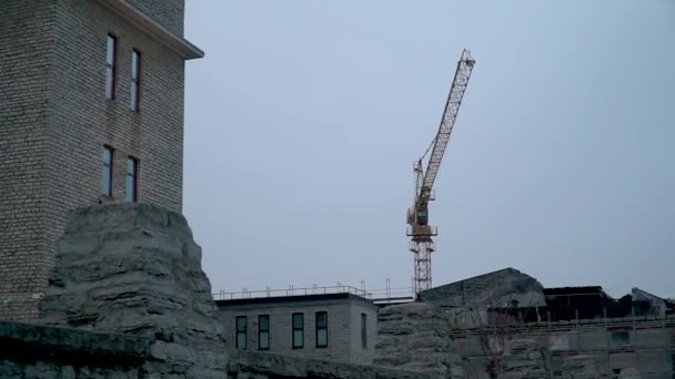 La grúa trabaja en un sitio de construcción en un clima sombrío todo gris — Vídeos de Stock