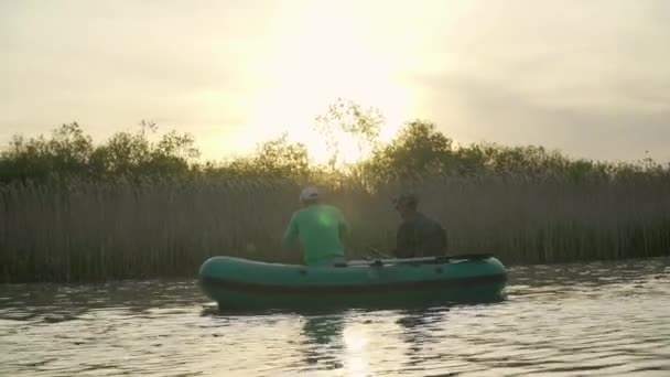 Gün batımında iki balıkçı şişme bir tekneden balık yakalar. — Stok video