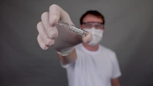 Флакон с вакциной против вируса и коронавируса, человек держит в руках — стоковое видео