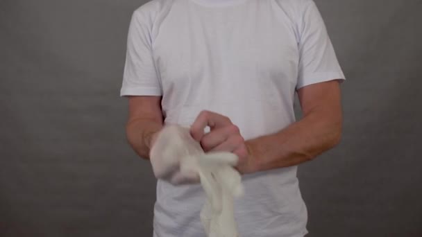 Ένας άντρας φοράει προστατευτικά ιατρικά γάντια για να προστατευτεί από τον ιό της στέψης. — Αρχείο Βίντεο