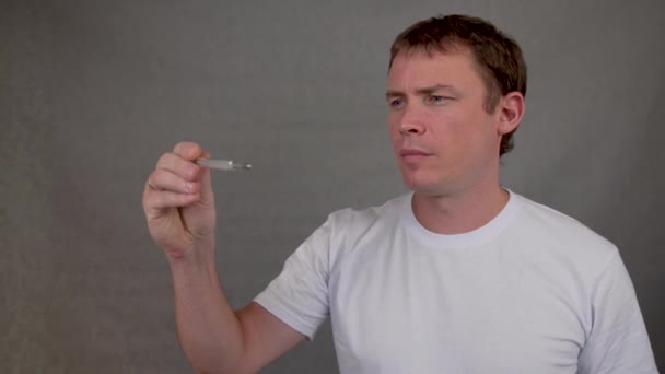 Man meet lichaamstemperatuur kijkt naar een thermometer en zet een masker op zijn gezicht — Stockvideo