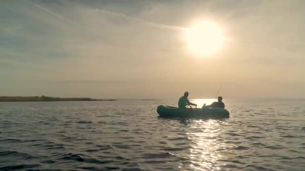 Dos pescadores navegando en un barco en un lago al atardecer — Vídeos de Stock