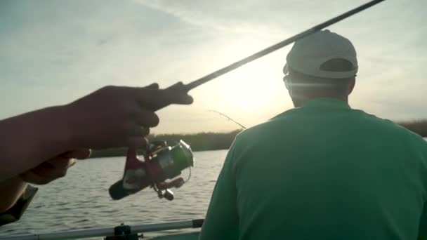 Pescatore pesca su un lago al tramonto, vista dal retro — Video Stock